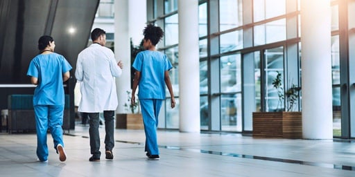 Tres médicos caminando juntos en un hospital.